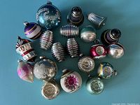 Overhead photo showing all loose vintage ornaments in varied shapes, colors, and styles including ridged, reflective, floral indented and bell shapes.