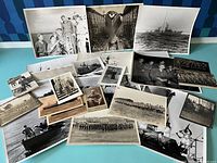 Image showing a wide variety of 22 black and white vintage military photographs displayed on a blue surface, including ship photos, group pictures of soldiers and naval officers, and military scenes.