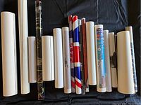 Overview photo showing 16 rolled items of mixed size and design including one red, white and blue roll and colorful printed rolls