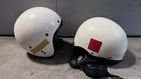 Two white vintage cafe style race helmets side by side, showing overall condition and style.