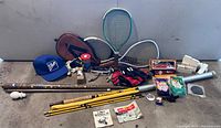 Full overview of the lot showing fishing rod, rackets, balls, gloves, cap, slides, cane/pool cue and various small sports-related items.