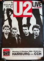 Full front view of the concert poster showing the band members, tour title, date, and location with visible wear and damage.