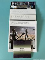 Photo showing three U2 Propaganda World Tour magazines, two Mini International music magazines stacked behind.