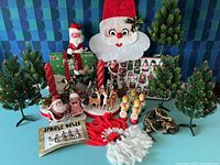 Full lot overview showing vintage pine trees, Santa wall hanging, candle holders, figurines, ornaments and knotted yarn decor.
