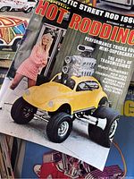 Close up photo of Hot Rodding magazine with yellow car and large supercharged engine, November 1977 edition, featuring a woman in retro dress