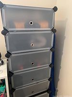 Full view of six black modular drawers stacked vertically with frosted fronts and a round finger hole on each drawer front.