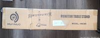 Box of HUANUO dual monitor table stand, Model HNCM1 with graphic showing dual monitor arms.