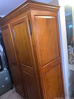 Side and angled view of the pine wood armoire showing paneling and crown molding details.