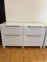 Front view of white IKEA Besta cabinet with four drawers and chrome handles
