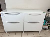 Front view of the white IKEA Besta cabinet with four front panels: two drawers above and two door cabinets below, all with silver curved handles.