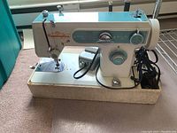 Full view of Remington electric sewing machine on its carrying case.