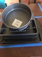 Photo showing stack of bakeware including a springform pan on top and multiple rectangular pans below