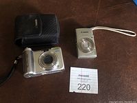 Two cameras (PowerShot A610 and ELPH 180) and black case on table