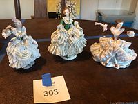 Three Dresden porcelain lace figurines displayed together on table