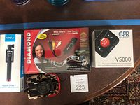 All items from the lot showing boxes of Diamond one-touch video capture, CPR call blocker, Sony digital camera in leopard case, and Mpow monopod package