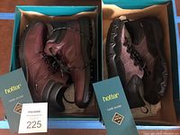 Photo showing two pairs of Hotter shoes, ankle boots and sneakers, each in a blue Hotter branded box with care guides.