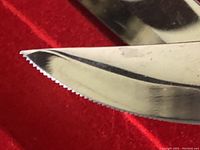 Close-up of serrated tip of steak knife blade showing sharp serrations and pointed tip.