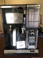Front view of the Ninja coffee maker showing the stainless steel and black finish, the glass or thermal carafe, the water reservoir, and the control panel.