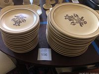 Stacked Pfaltzgraff Village dinner and salad plates showing floral pattern and beige background with dark trim.