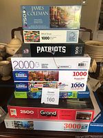 Stacked boxed jigsaw puzzles showing brand names, themes, and piece counts