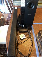 Soundbar and subwoofer with cables lying on a table.
