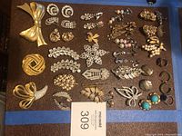 Overview of assorted brooches, pins, clip on earrings and rhinestone jewelry pieces