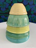 Stacked Bauer pottery mixing bowls in five different pastel colors showing size gradient and ribbed texture.