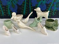 All 10 pieces arranged on a white surface, front and side views showing a variety of vintage glazed animal and shoe pottery items including a lamb, duck, birds, and planters.