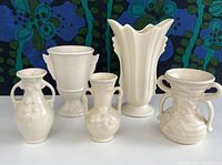 Front view of all five cream glazed vintage vases, showing different shapes and styles with double handles and sculptural details
