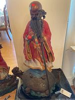 Full front view of painted bronze statue showing figure standing on turtle base