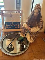 Full view of the set showing the doll, mini loom, silver tray, small shoes, and metal hook on hardwood floor.