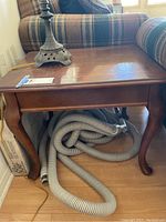 Top and side view of solid wood end table showing rectangular top with scratches and curved legs.
