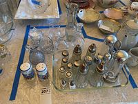 Various glass salt and pepper shakers, ceramic salt and pepper shakers with blue floral design, clear glass cruets, and the glass baking dish shown among other dishes on a table.