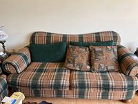 Front view of the plaid green and tan fabric sofa with multiple cushions.