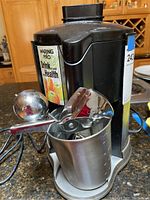 Photo of black Waring Pro juicer with metal measuring cup and juicing utensil on top