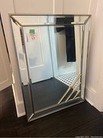 Full view of the beveled border wall mirror showing the angled geometric lines on the lower right and the mirror's reflective quality.