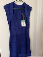 Front side view of the blue French Connection dress on hanger showing the structured bandage detailing and cap sleeves with tags attached.