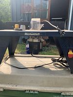 Overall view of Mastercraft router table with router and power cord underneath.