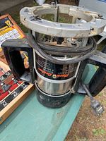 Photo showing Black & Decker router with power cord wrapped around the body, placed on a green table outdoors.