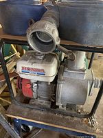 Photo of Honda WB30X water pump with attached black hoses on metal frame.