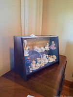 Side angle of wood cabinet with plastic cover showcasing miniature set inside on two shelves