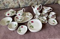 Full set of Midwinter Modern Fashion Rose China including plates, bowls, cups, pots, and serving pieces arranged on carpet in front of sofa.