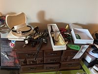 Overview of the jewelry box with multiple watches, brooches, and other costume jewelry arranged on top and around it.
