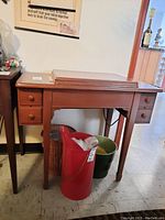 Full view of the wooden sewing table closed, showing the front with four drawers and open space underneath