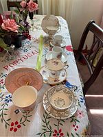 Photo showing six vintage teacups and saucers on a table, varying designs including pink marbled and floral patterns