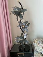 Full view of one lamp showing black swirl base and three leaf-shaped shade clusters