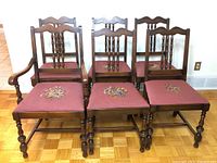 Full set of 6 chairs with 1 captain chair in front left and 5 standard chairs behind, all with pink needlepoint floral seats