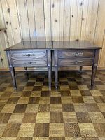 Pair of Deilcraft wooden end tables side-by-side against wood-paneled wall, showing front with two drawers each and ornate handles.