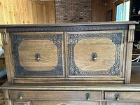 Front view of Gibbard solid walnut cupboard showing two carved doors with decorative metal handles and detailed carved frame accents