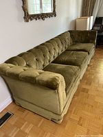 Three-quarter front view showing button-tufted back and rolled arm